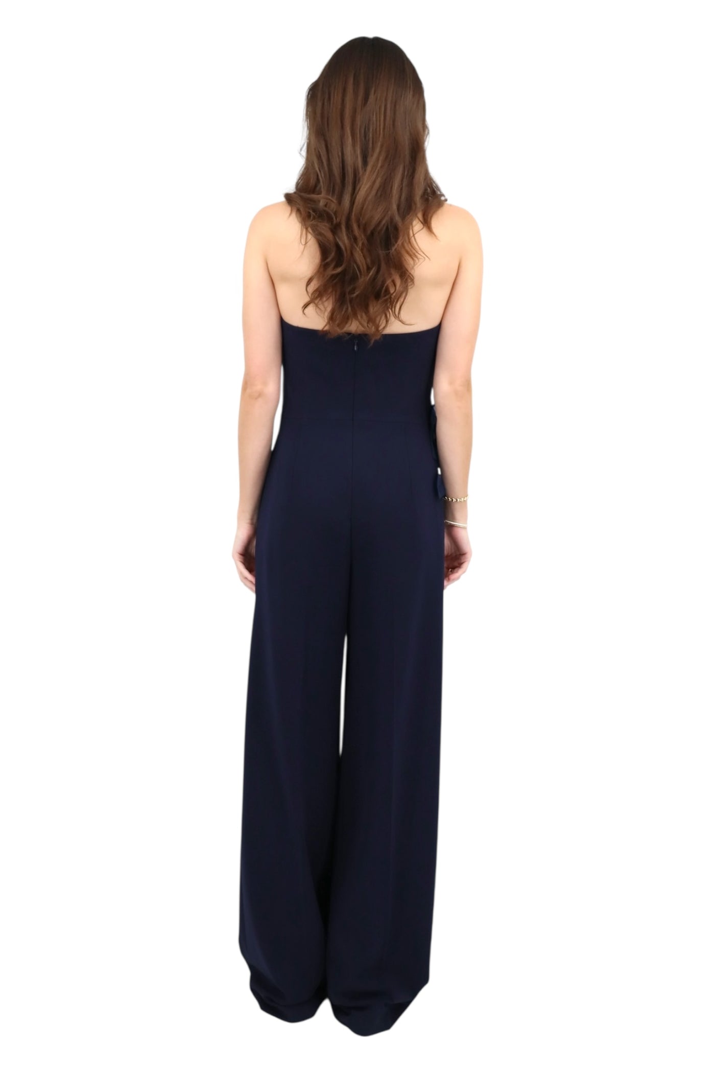 Woman wearing a navy blue strapless jumpsuit on a white background